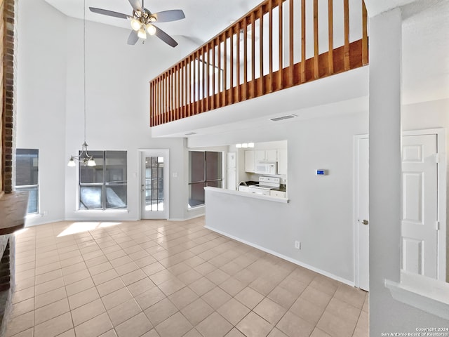 unfurnished living room featuring a towering ceiling, ceiling fan, and light tile patterned floors