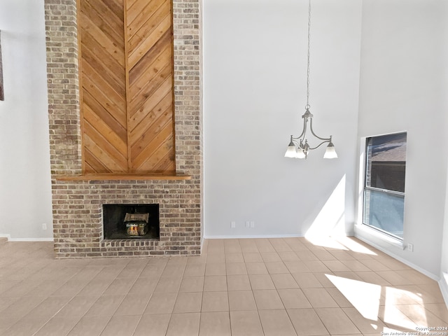 unfurnished living room featuring light tile patterned floors, a fireplace, wooden walls, and a chandelier