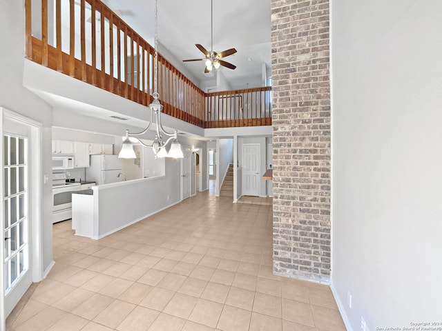 tiled foyer featuring ceiling fan with notable chandelier, a towering ceiling, and sink