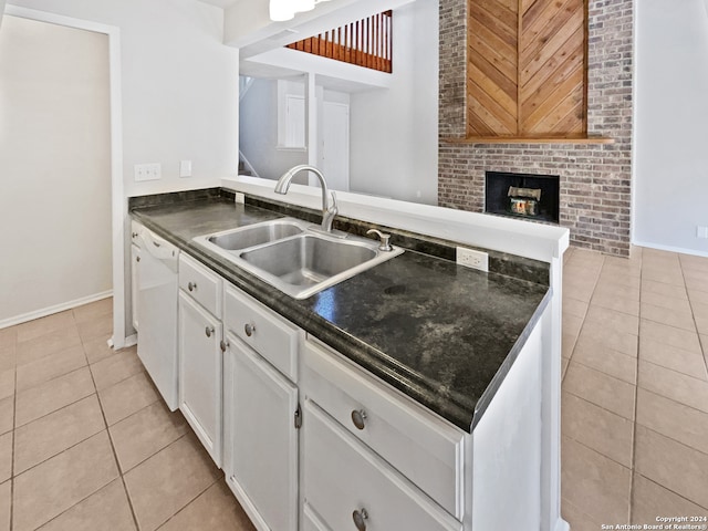 kitchen featuring light tile patterned flooring, white dishwasher, sink, kitchen peninsula, and white cabinetry