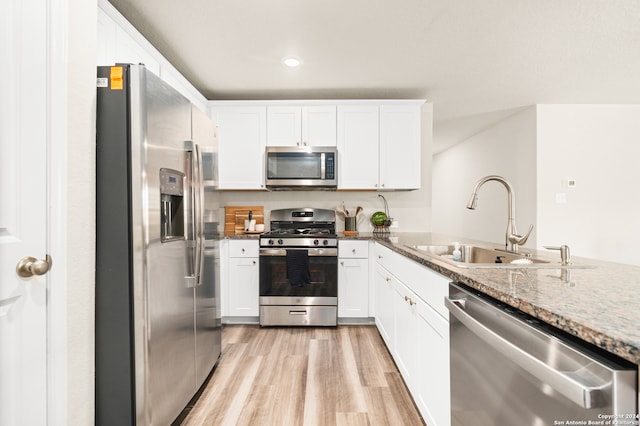 kitchen with appliances with stainless steel finishes, light hardwood / wood-style floors, sink, and white cabinets