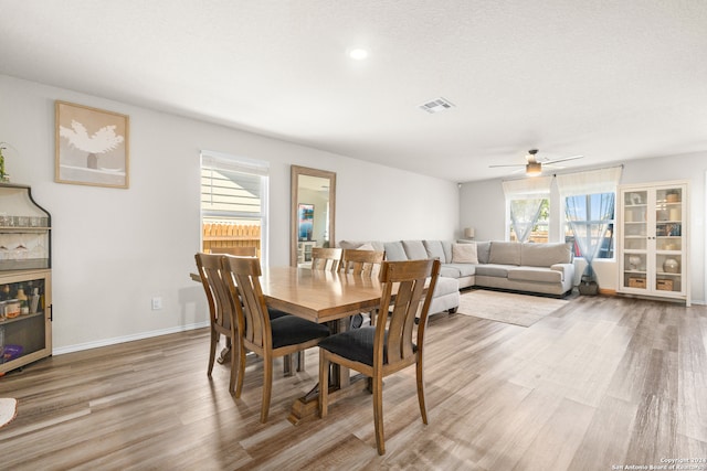 dining area with light hardwood / wood-style floors, ceiling fan, and a textured ceiling