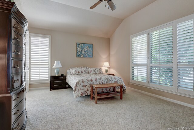 carpeted bedroom featuring ceiling fan, vaulted ceiling, and multiple windows