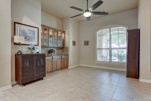 bar with light tile patterned flooring, ceiling fan, and decorative backsplash