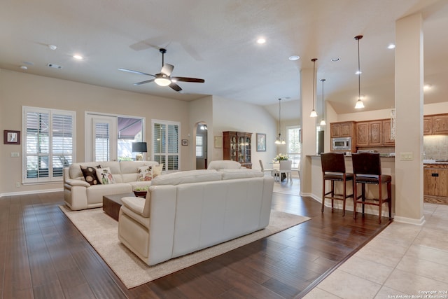 living room featuring ceiling fan with notable chandelier, lofted ceiling, and light hardwood / wood-style floors