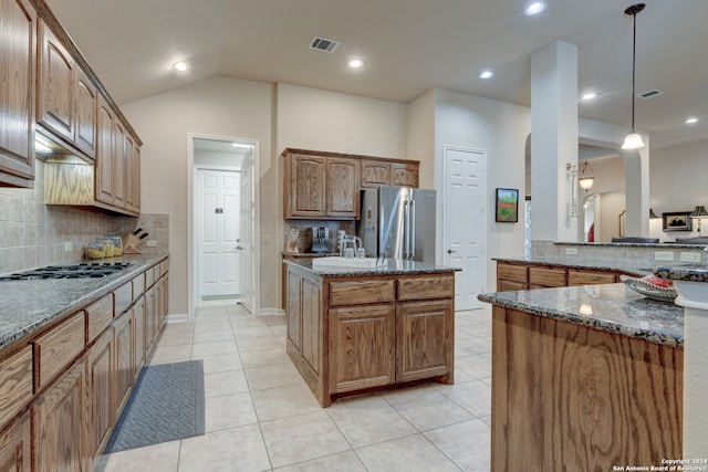 kitchen with tasteful backsplash, stainless steel appliances, a center island, dark stone countertops, and vaulted ceiling