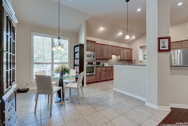 kitchen featuring pendant lighting, lofted ceiling, appliances with stainless steel finishes, an inviting chandelier, and decorative backsplash