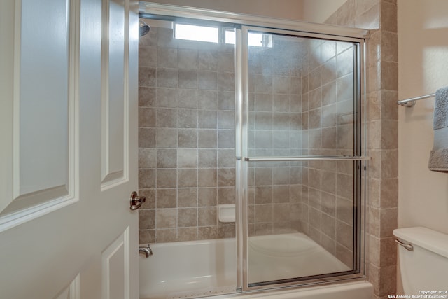 bathroom featuring shower / bath combination with glass door and toilet