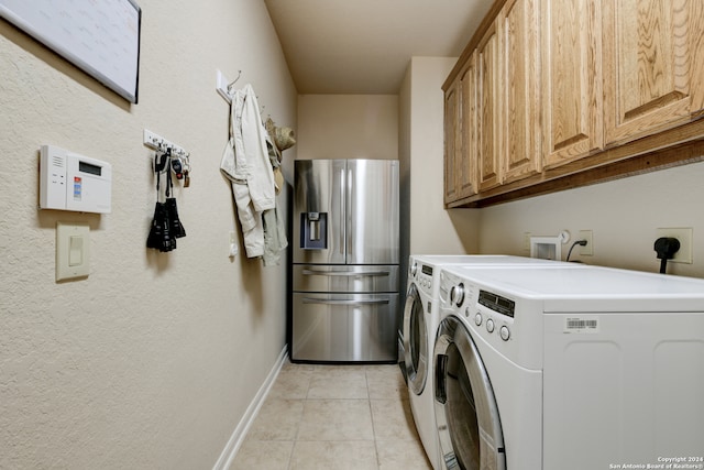 clothes washing area with independent washer and dryer, light tile patterned flooring, and cabinets