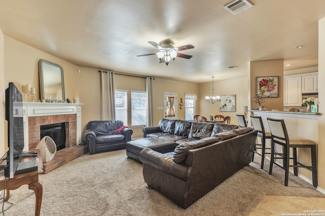 carpeted living room with ceiling fan with notable chandelier and a fireplace