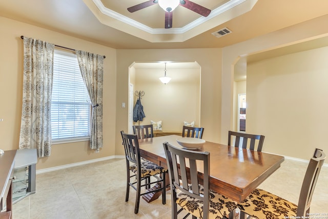 tiled dining room featuring ceiling fan, a raised ceiling, and ornamental molding