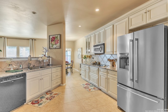 kitchen with light tile patterned floors, sink, tasteful backsplash, cream cabinetry, and stainless steel appliances