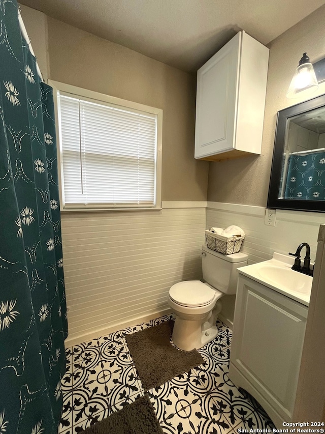 bathroom featuring tile walls, vanity, toilet, and tile patterned floors