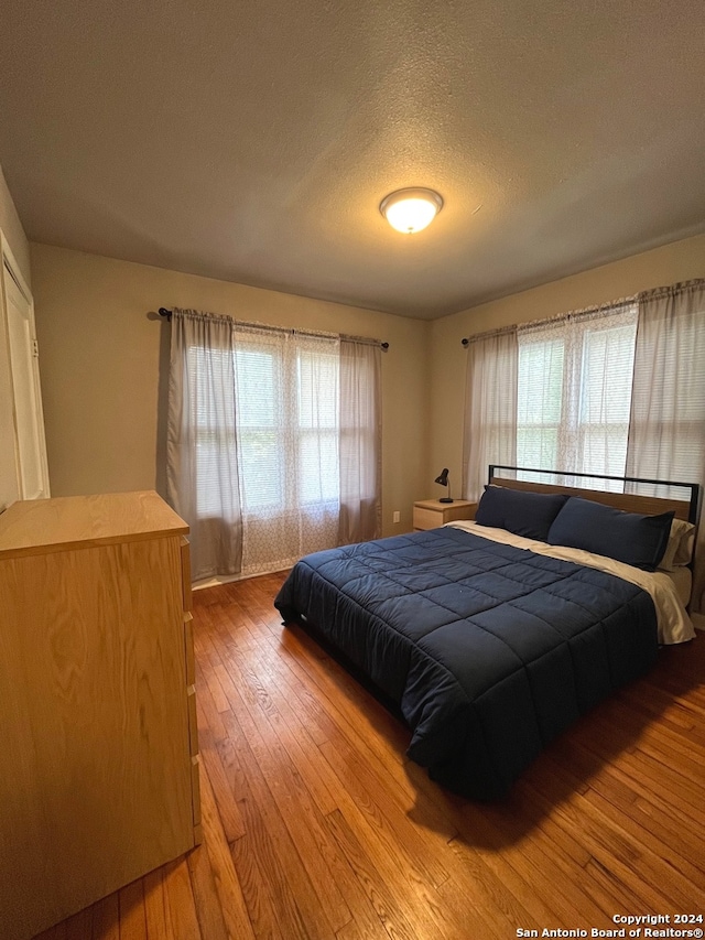 bedroom featuring wood-type flooring, a textured ceiling, and multiple windows