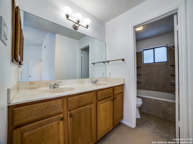 full bathroom with toilet, vanity, a textured ceiling, and tiled shower / bath