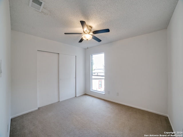 unfurnished bedroom with carpet, a textured ceiling, a closet, and ceiling fan