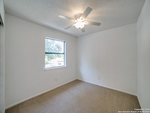 empty room with ceiling fan, carpet floors, and a textured ceiling