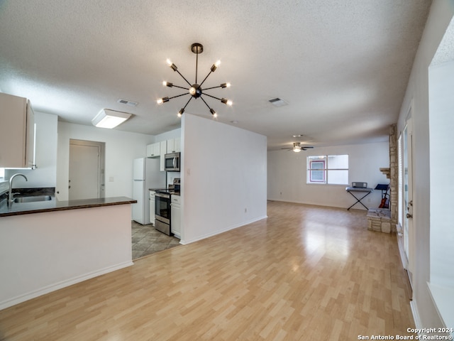 unfurnished living room featuring sink, ceiling fan with notable chandelier, light hardwood / wood-style floors, and a textured ceiling