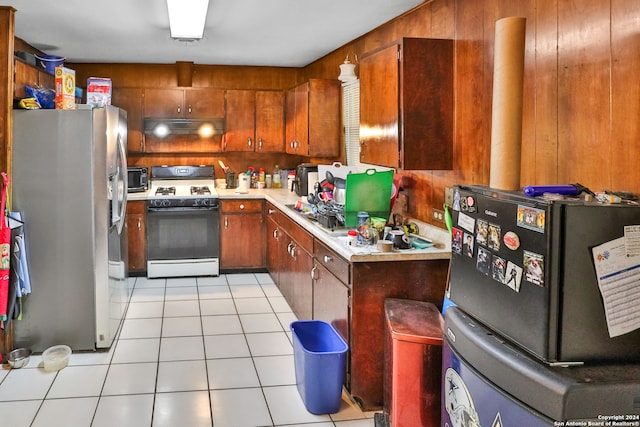 kitchen with refrigerator, wooden walls, gas range gas stove, and stainless steel fridge with ice dispenser