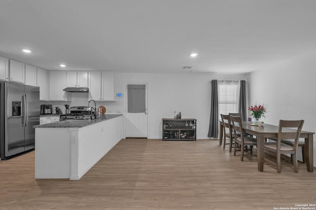 kitchen featuring white cabinets, appliances with stainless steel finishes, kitchen peninsula, and dark stone counters