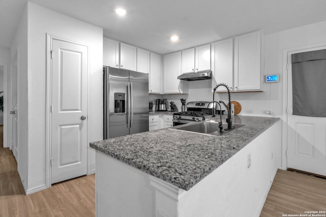 kitchen with dark stone counters, light hardwood / wood-style floors, stainless steel appliances, and white cabinets