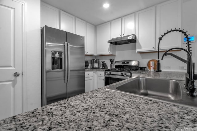 kitchen with appliances with stainless steel finishes, stone counters, sink, and white cabinetry