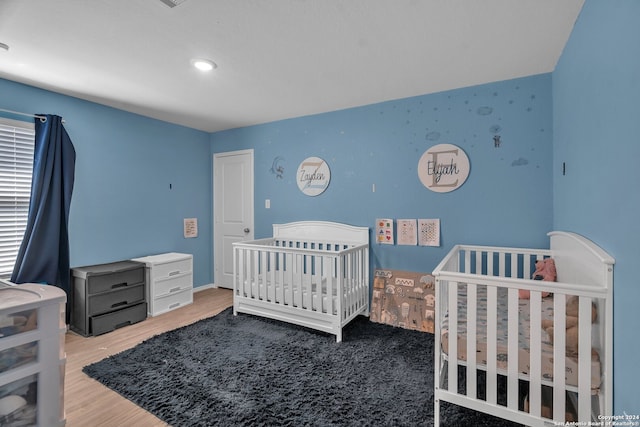 bedroom with a nursery area and hardwood / wood-style floors