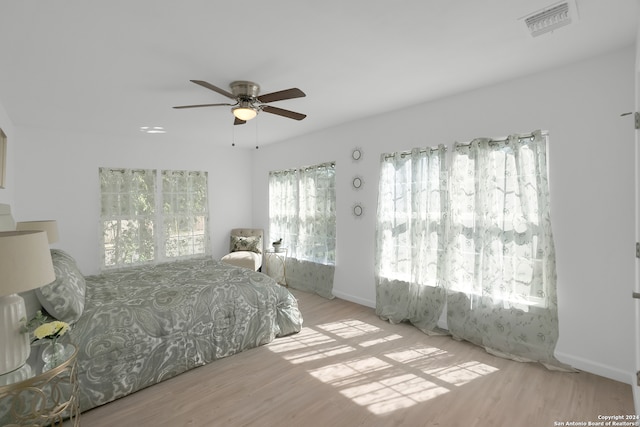 bedroom featuring ceiling fan, light wood-type flooring, and multiple windows