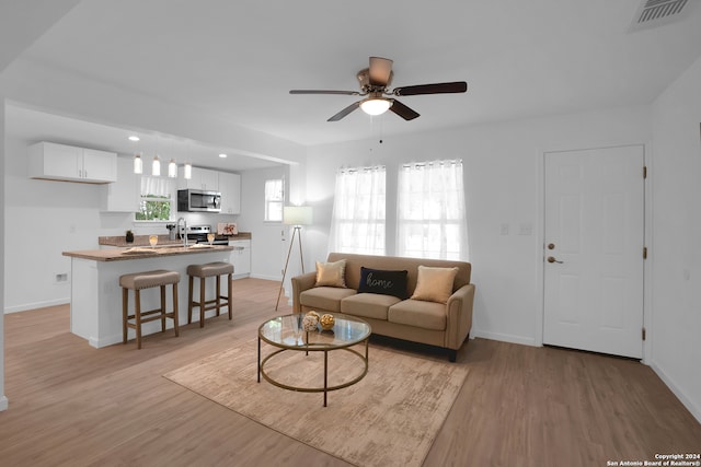 living room with ceiling fan and light hardwood / wood-style floors