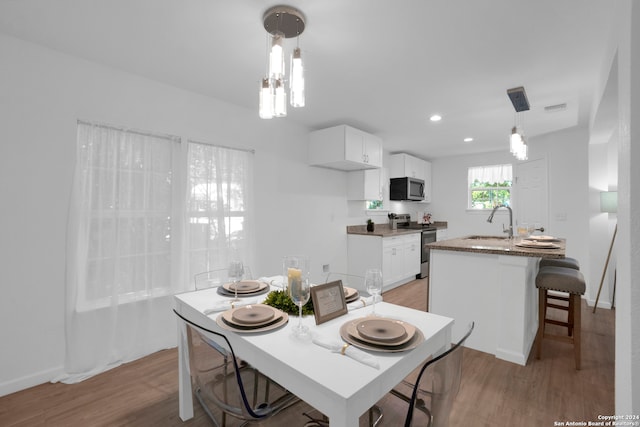 dining area with an inviting chandelier, light hardwood / wood-style flooring, and sink