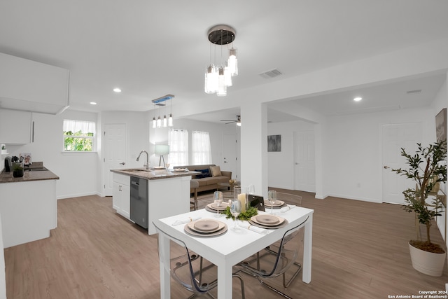 dining area featuring light hardwood / wood-style floors, ceiling fan with notable chandelier, and sink