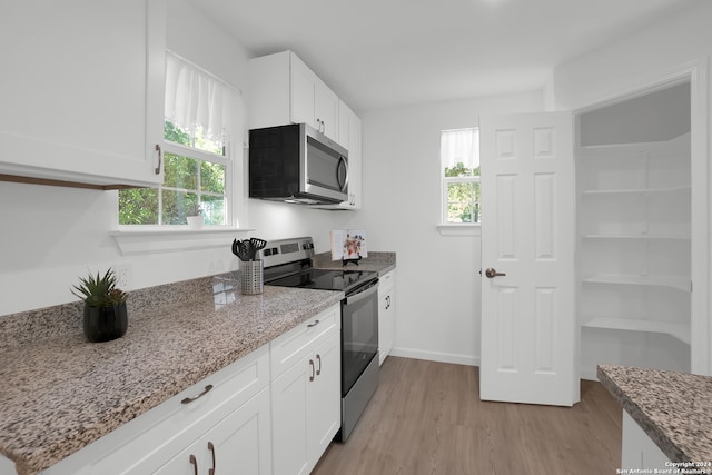 kitchen with light wood-type flooring, a healthy amount of sunlight, stainless steel appliances, and white cabinets