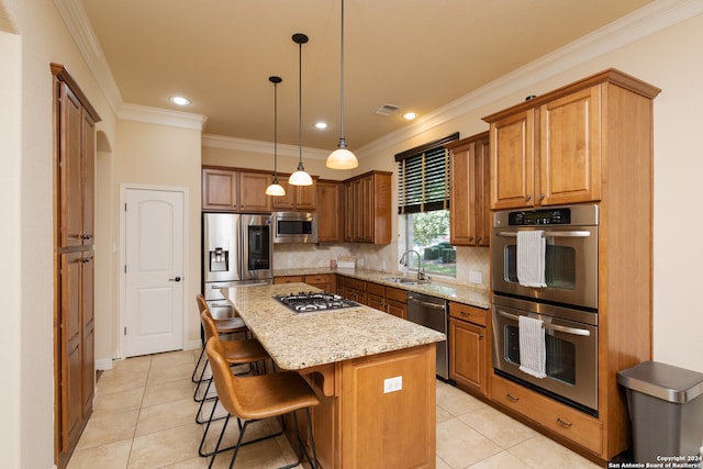 kitchen featuring pendant lighting, light stone counters, a center island, appliances with stainless steel finishes, and crown molding