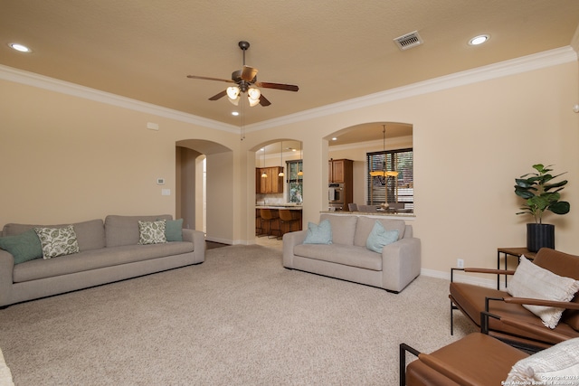 carpeted living room featuring crown molding and ceiling fan with notable chandelier