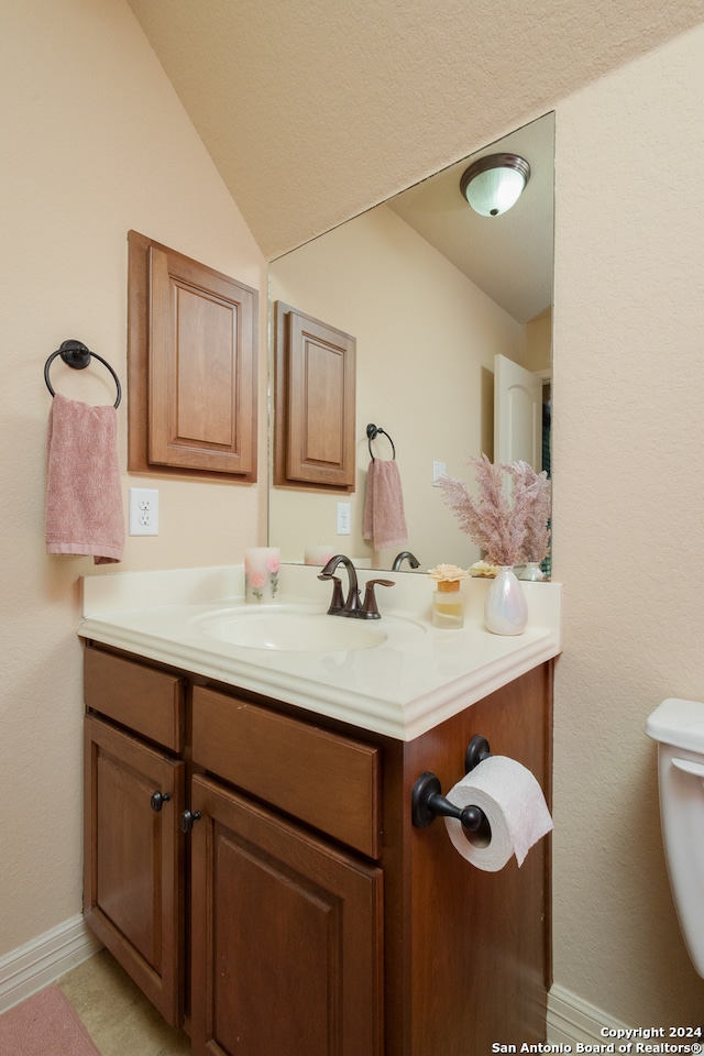 bathroom with lofted ceiling, vanity, and toilet