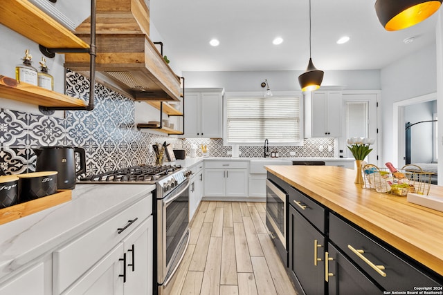 kitchen featuring stainless steel appliances, hanging light fixtures, decorative backsplash, and white cabinetry