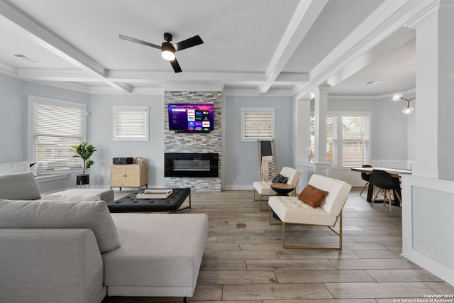 living room featuring ceiling fan, beamed ceiling, a stone fireplace, light hardwood / wood-style flooring, and coffered ceiling