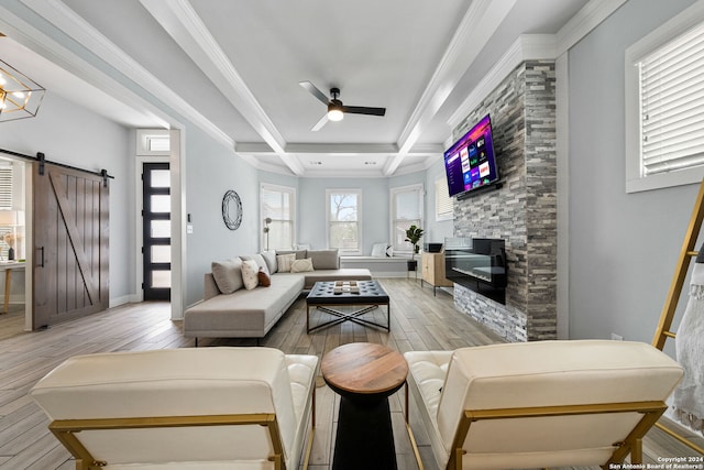 living room with light wood-type flooring, crown molding, and a barn door