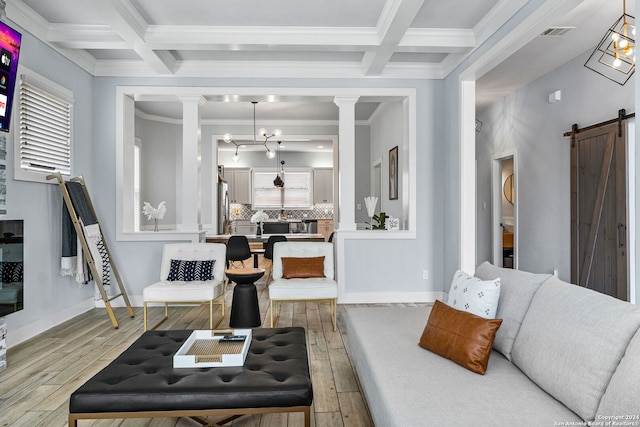 living room featuring coffered ceiling, ornamental molding, light hardwood / wood-style flooring, and a barn door