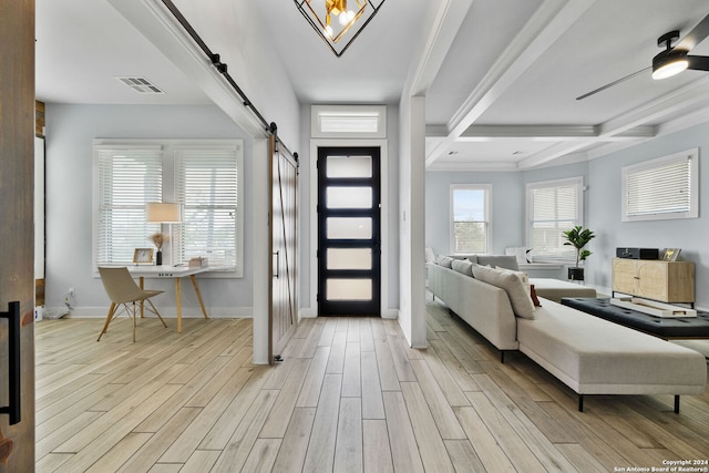 foyer featuring light wood-type flooring, beamed ceiling, a barn door, crown molding, and ceiling fan