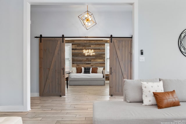 bedroom with light hardwood / wood-style flooring, wooden walls, and a barn door