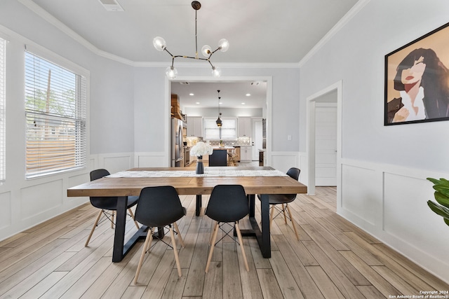 dining area featuring crown molding, an inviting chandelier, and light hardwood / wood-style flooring