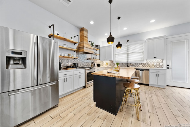 kitchen featuring white cabinetry, a kitchen island, stainless steel appliances, decorative light fixtures, and wooden counters