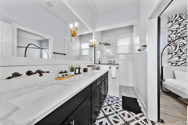 bathroom featuring a notable chandelier, vanity, a tile shower, and hardwood / wood-style flooring