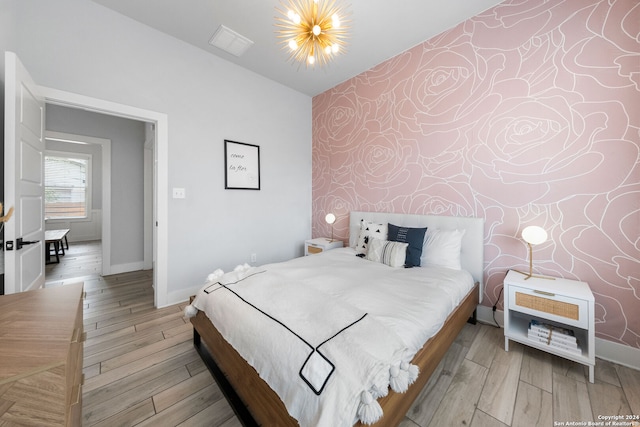 bedroom featuring vaulted ceiling, light wood-type flooring, and a chandelier