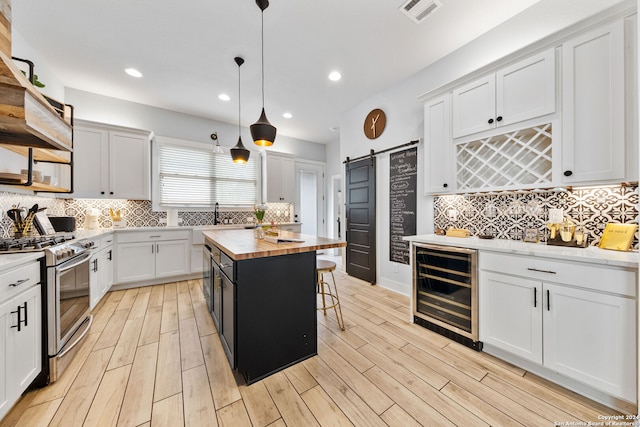 kitchen featuring wooden counters, a kitchen island, decorative light fixtures, a barn door, and gas stove