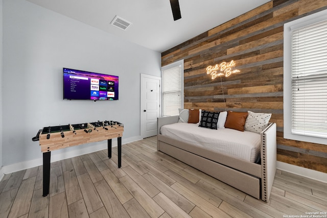 bedroom with wooden walls, ceiling fan, and light wood-type flooring