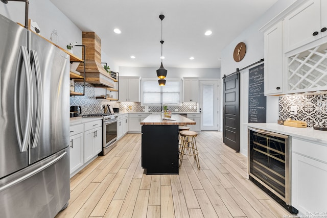 kitchen featuring a barn door, white cabinetry, wine cooler, and stainless steel appliances