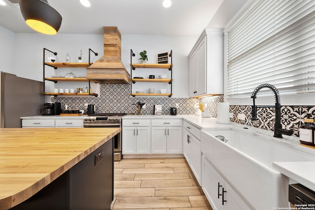 kitchen featuring sink, white cabinetry, appliances with stainless steel finishes, custom range hood, and wood counters