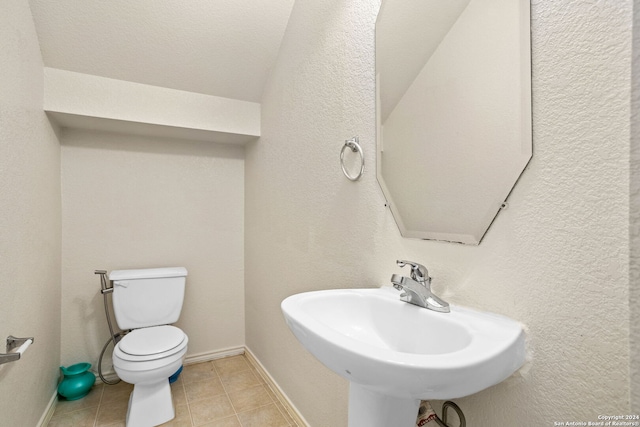 bathroom with toilet, sink, and tile patterned floors